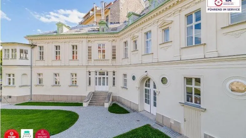 Eindrucksvolles klassisches Gebäude mit gepflegtem Rasen und gepflastertem Weg im Außenbereich.