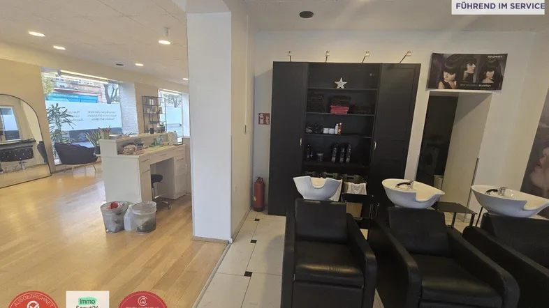 Moderner Friseursalon mit mehreren Waschbecken und Arbeitsplätzen, ausgestattet mit dunklen Schränken und hellem Holzboden.
