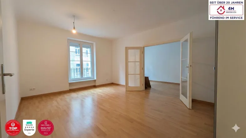 Helles Wohnzimmer mit Parkettboden und Zugang zu einem französischen Balkon, ideal für entspannte Stunden.