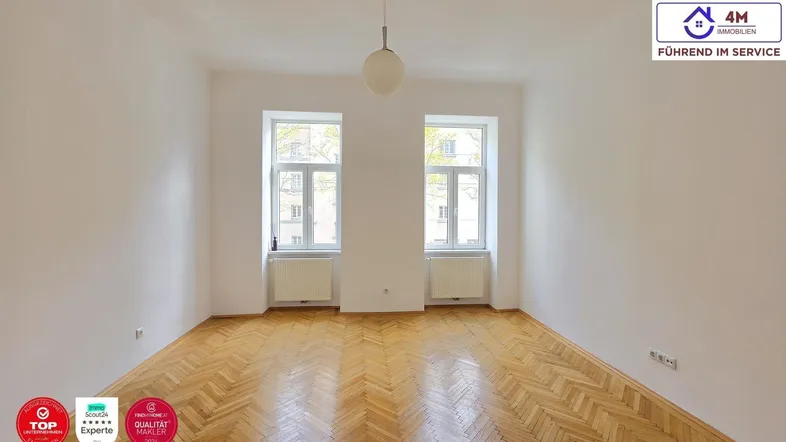 Helles Zimmer mit Fischgrätparkett und zwei großen Fenstern, ideal als Wohn- oder Schlafzimmer.