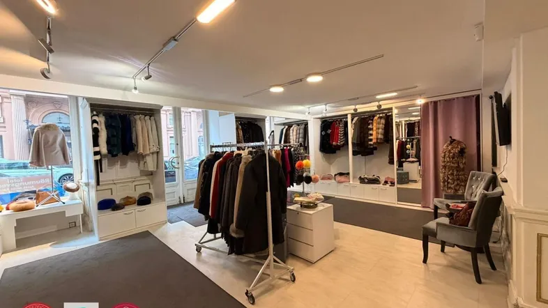 Geräumiger Verkaufsraum mit moderner Beleuchtung, Kleiderständern und Schaufensterblick zur Straße.