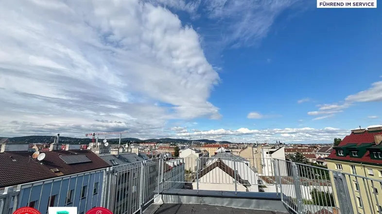 Weitläufiger Blick über die Dächer der Stadt mit blauem Himmel und Wolken.