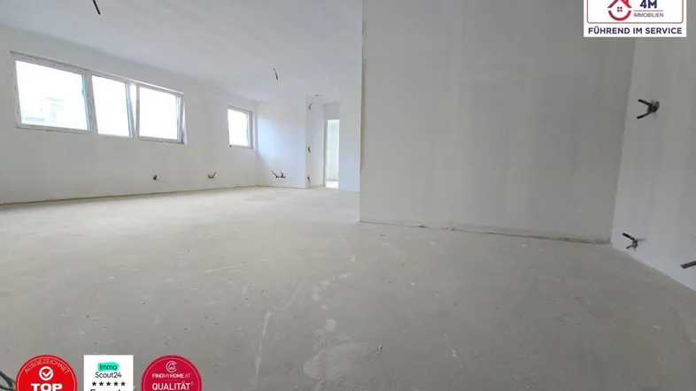 Geräumiger, unfertiger Innenraum mit großen Fenstern, bereit für den Ausbau und die individuelle Gestaltung.