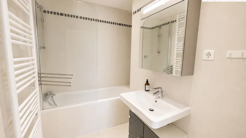 Modernes Badezimmer mit Badewanne, Duschabtrennung, Waschbecken und beheiztem Handtuchhalter.