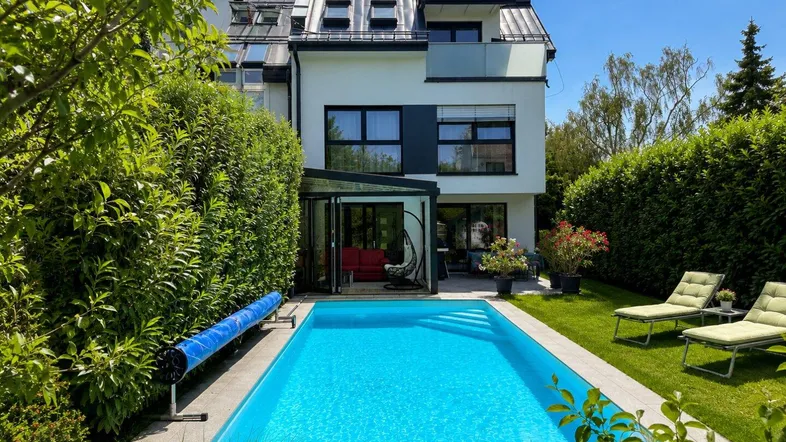 Modernes Haus mit Garten, privatem Pool und Liegeflächen, umgeben von grünen Hecken.