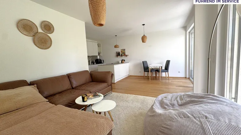 Heller, offener Wohn- und Essbereich mit integrierter Küche, Parkettboden und Zugang zur Terrasse.
