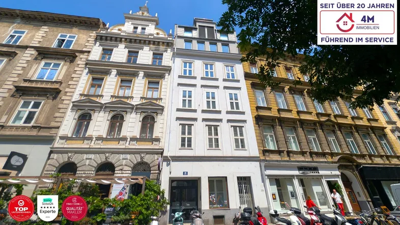 Historische Fassade eines Mehrfamilienhauses in einer belebten Stadtstraße mit moderner Architektur.