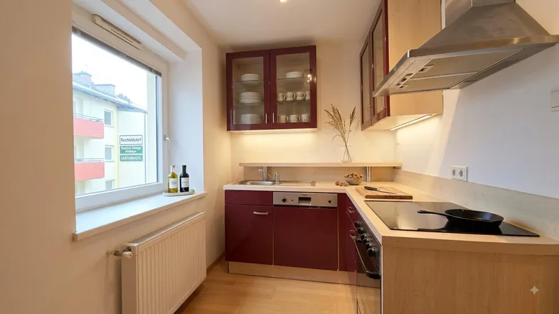 Moderne Küche mit weinroten Schränken, hellem Holz und Fensterblick auf die Umgebung.