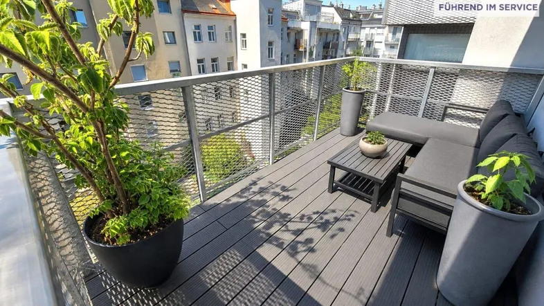 Geräumiger Balkon mit modernen Terrassendielen, bequemen Outdoor-Möbeln und Blick auf die Stadt.