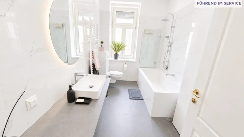 Modernes Badezimmer mit Marmorfliesen, Badewanne, Dusche und großem Spiegel.