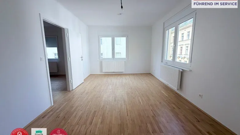 Helles, leeres Zimmer mit Parkettboden und zwei Fenstern, bereit zur individuellen Gestaltung.