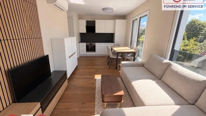 Heller offener Wohn-Essbereich mit integrierter Küche, Holzboden und Zugang zur Terrasse.