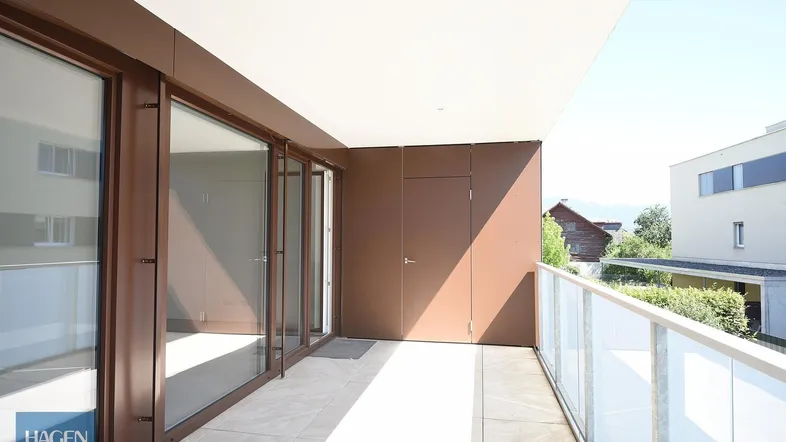 Geräumiger Balkon mit Glasgeländer und Zugang zu den Innenräumen, ideal für Entspannung im Freien.