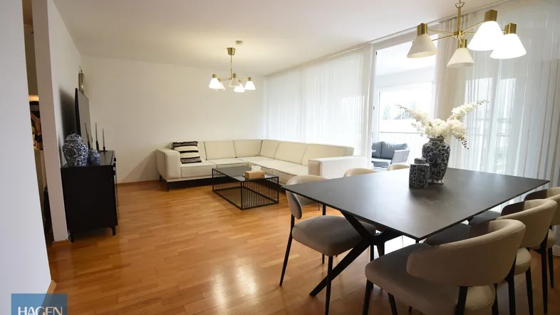 Helles Wohn- und Esszimmer mit Parkettboden, moderner Einrichtung und Zugang zum Balkon.