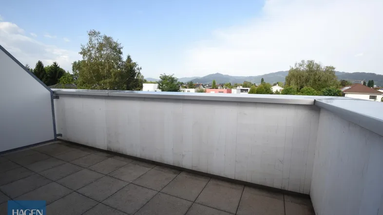 Große geflieste Terrasse mit weitem Blick auf die umliegende Landschaft und Berge.