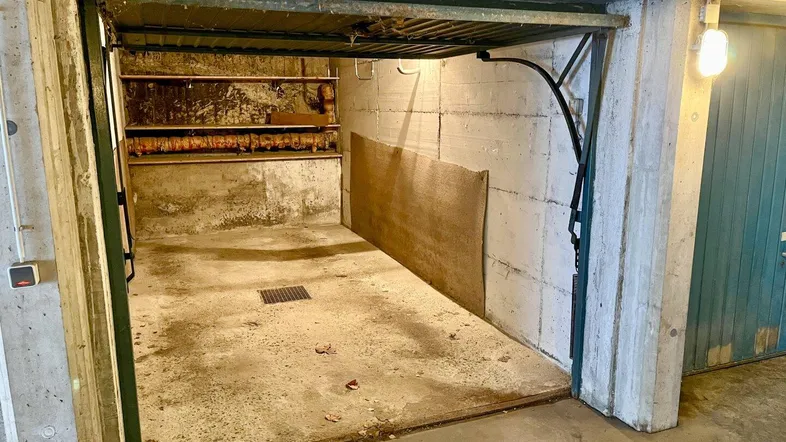 Offene Garage mit Betonwänden und schmutzigem Boden, bereit zur Nutzung.