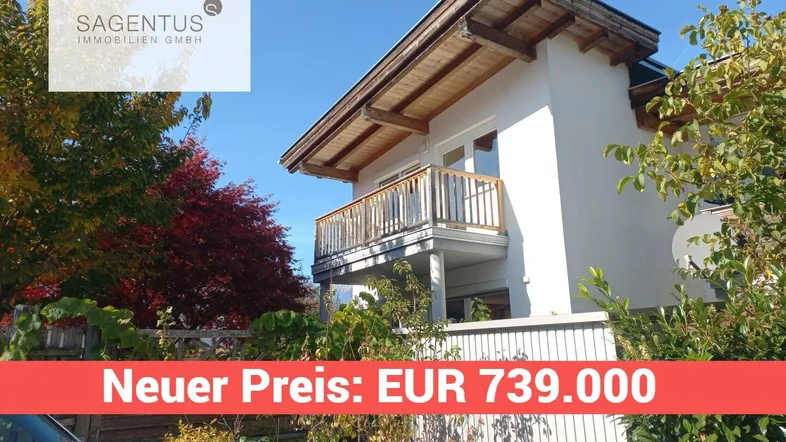 Modernes Haus mit Holzbalkon und sichtbaren Holzelementen unter dem Dach in sonniger Lage.