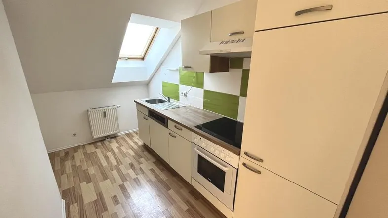 Helle Küche im Dachgeschoss mit Einbauküche, Laminatboden und Dachfenster.