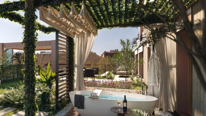 Luxuriöses Outdoor-Badezimmer mit freistehender Badewanne unter einer begrünten Pergola im Gartenbereich.
