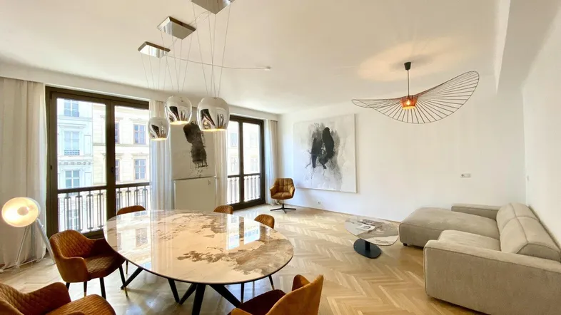 Helles Wohn- und Esszimmer mit Fischgrätparkett, modernen Leuchten und großen Fenstern.