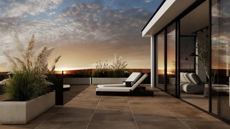 Geräumige Dachterrasse mit Liegestühlen und Pflanzen, ideal zum Entspannen bei Sonnenuntergang.