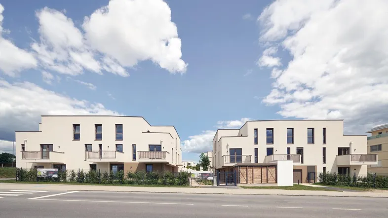 Moderne Mehrfamilienhäuser mit heller Fassade und Balkonen an einer Straße gelegen.