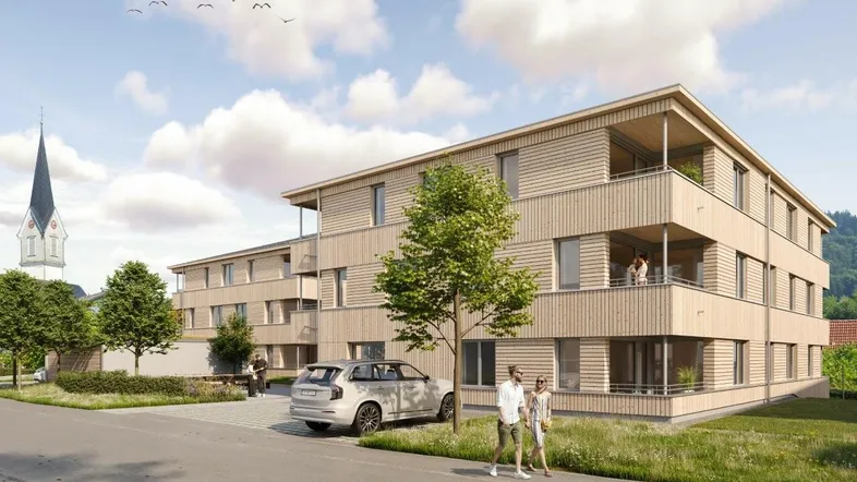 Mehrfamilienhaus in Holzbauweise mit Balkonen, darunter eine Person schlendert und ein Auto geparkt ist (Riedstrasse, Hohenweiler).