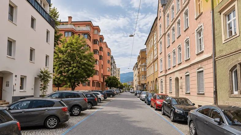 Belebte Wohnstraße mit parkenden Autos und historischen sowie modernen Gebäuden.