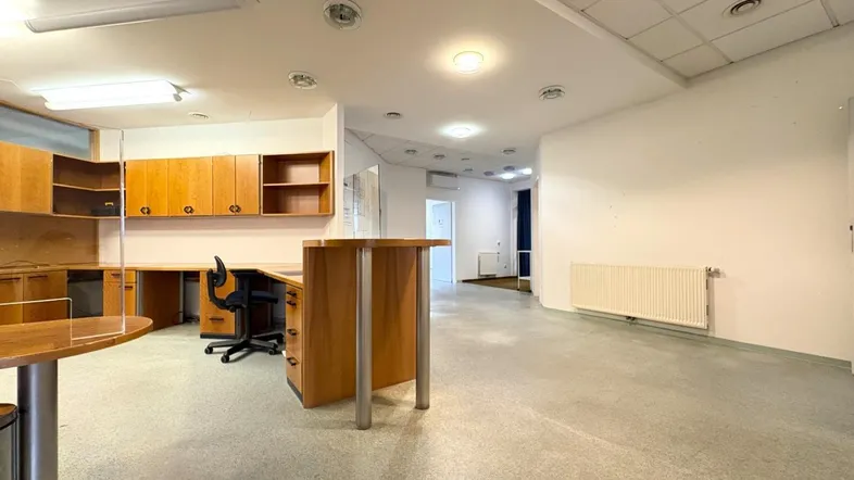 Geräumiger Büroraum mit Holzschränken, Schreibtischen und einem Empfangstresen in einem gewerblichen Gebäude.