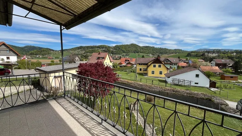 Geräumiger Balkon mit Blick auf die umliegende Landschaft und Häuser unter blauem Himmel.