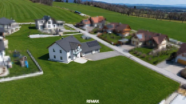 Luftaufnahme des Einfamilienhauses mit Doppelgarage und Photovoltaikanlage in ländlicher Umgebung.