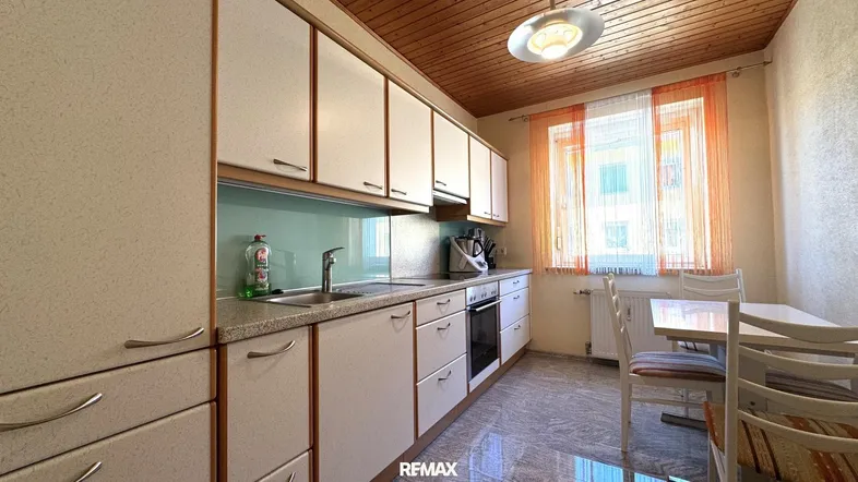 Helle Küche mit Einbauschränken, Essbereich und Holzdecke, ideal für Familien.