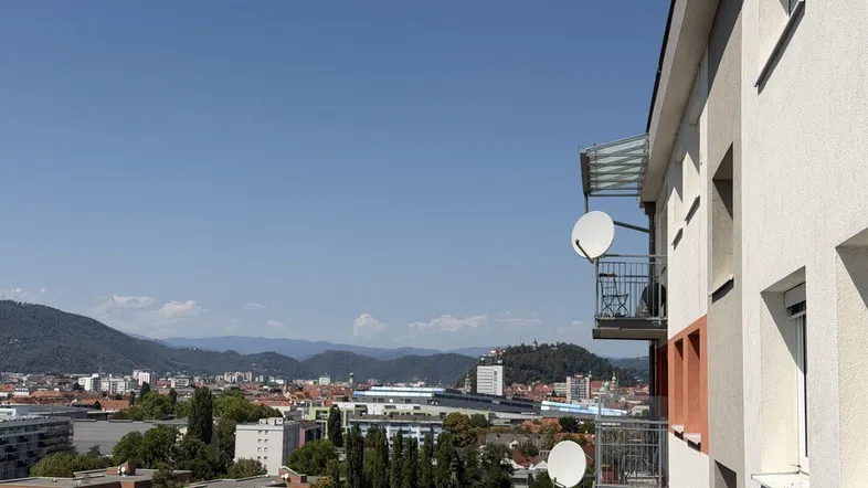 Panoramablick über die Stadt mit Bergen im Hintergrund und angrenzenden Balkonen.