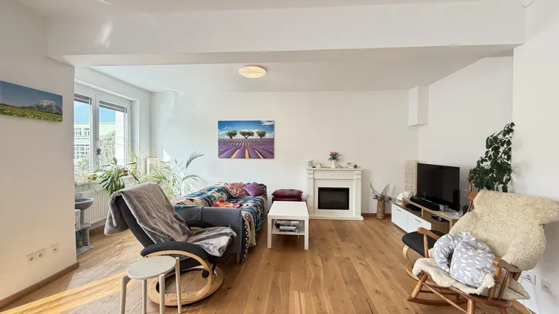 Helles Wohnzimmer mit Holzboden, Kamin und gemütlichen Sitzgelegenheiten, ideal zum Entspannen.