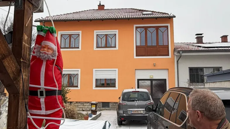 Außenansicht des Hauses mit orangefarbener Fassade im Winter, Schnee auf dem Hof und einem geparkten Auto.