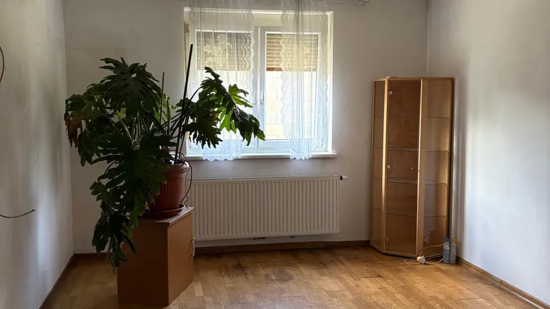 Helles Zimmer mit Parkettboden, Fenster und Deckenventilator, bereit zur individuellen Gestaltung.