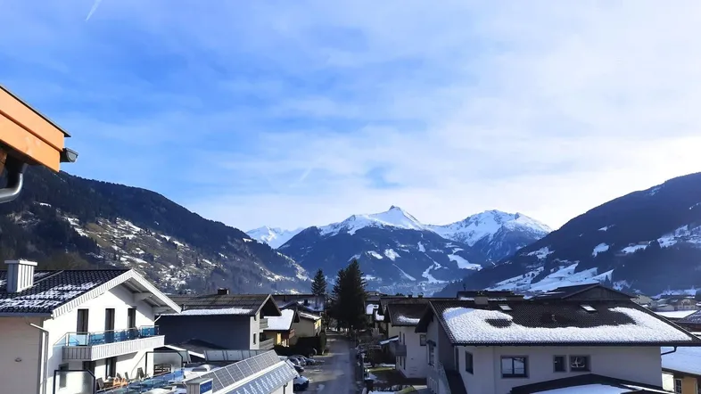 Panoramablick auf eine verschneite Berglandschaft mit traditionellen Häusern und klarem Himmel.
