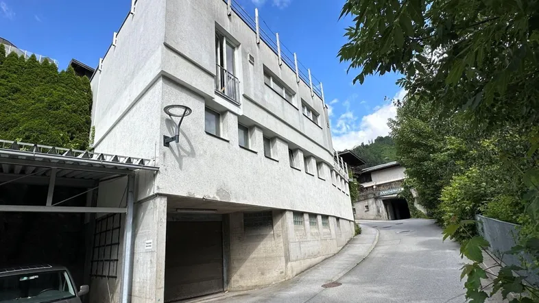 Modernes Gebäude mit mehreren Etagen und einer integrierten Garage an einer Hanglage.