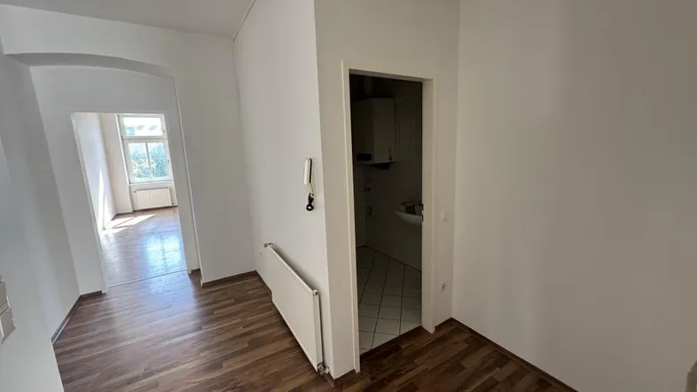 Heller Flur mit Laminatboden und Zugang zu weiteren Räumen sowie einem kleinen Badezimmer.