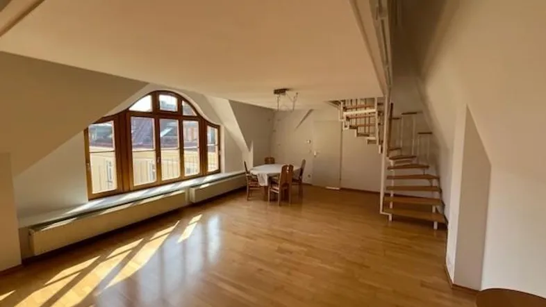 Helles Dachgeschoss-Wohnzimmer mit Holzboden, großer Fensterfront und Wendeltreppe, ideal für offenes Wohnen.