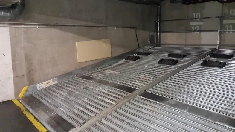 Mechanisches Parksystem in einer Tiefgarage mit Betonwänden und sichtbaren Installationen.
