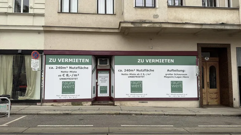 Fassade eines Geschäftsgebäudes mit großen Schaufenstern und "Zu vermieten"-Schildern im Erdgeschoss.