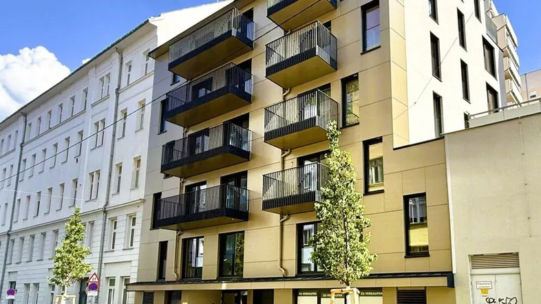 Modernes Mehrfamilienhaus mit mehreren Balkonen und zeitgenössischer Architektur in städtischer Umgebung.