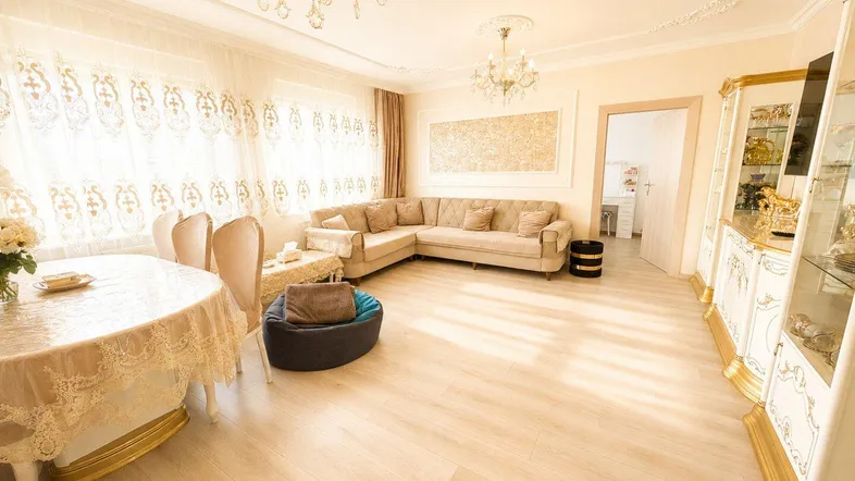 Helles Wohn- und Esszimmer mit eleganten Möbeln, Kronleuchtern und hellem Laminatboden.