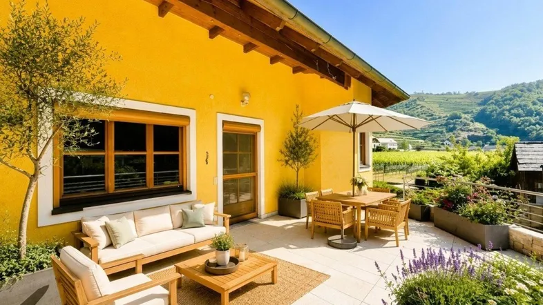 Große Sonnenterrasse mit bequemen Gartenmöbeln, Sonnenschirm und Blick auf die Weinberge.