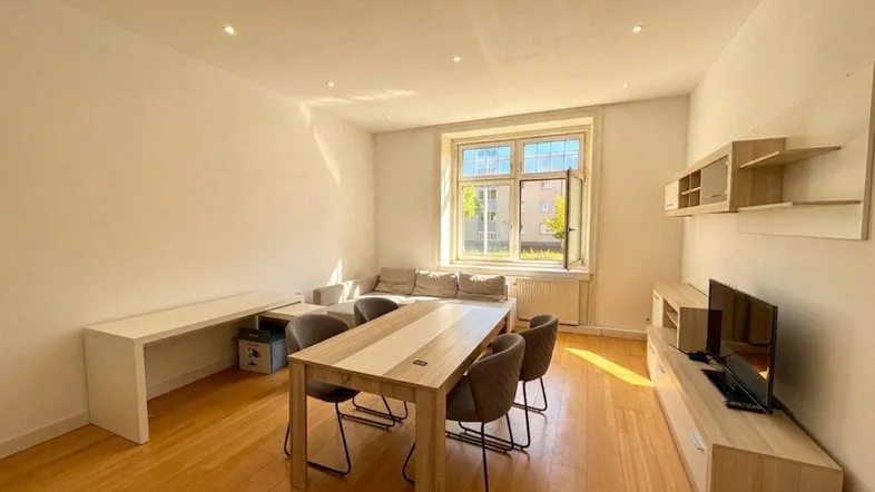 Heller Wohn- und Essbereich mit Holzboden, großem Fenster und moderner Einrichtung.