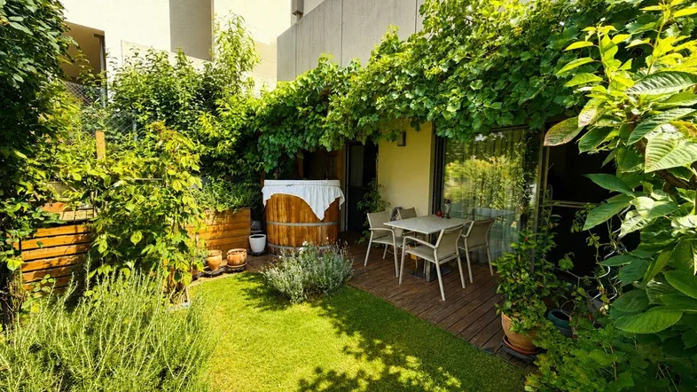 Idyllischer Gartenbereich mit Rasenfläche, üppiger Bepflanzung, einem Hot Tub und gemütlicher Sitzecke.