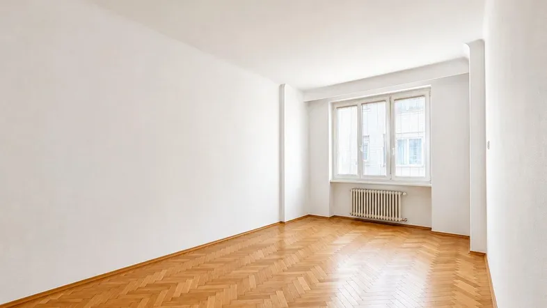 Helles Zimmer mit Fischgrätparkettboden und weiß gestrichenen Wänden, ideal für Wohn- oder Schlafbereich.
