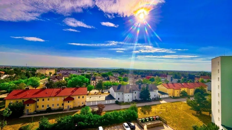 Panoramablick über die Stadt und die umliegende Landschaft unter strahlend blauem Himmel.