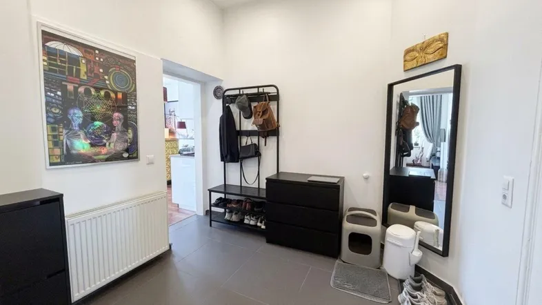 Heller Eingangsbereich mit Fliesenboden, Garderobe und einem großen Spiegel an der Wand.
